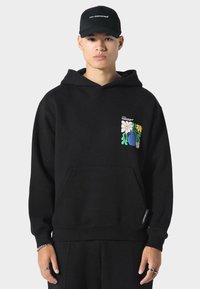 Mustapaita, joka on valmistettu pehmeästä kankaasta, etutaskulla ja vasemmassa rinnassa värikkäitä kukka-ompeluksia sekä ribbikudos hihansuissa.