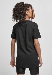 T-shirt en coton noir avec une coupe décontractée, des manches courtes et un ourlet droit. Texture lisse, sans motifs visibles ni détails matériels.