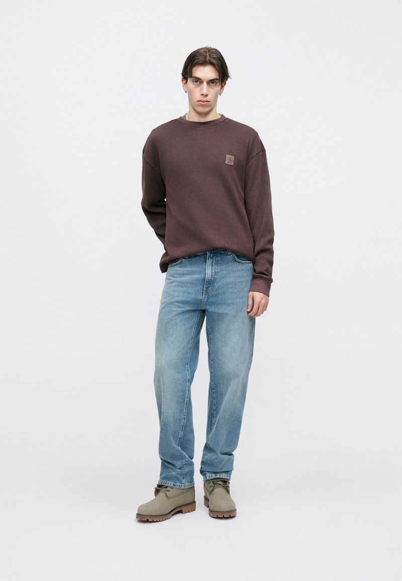 Brun ribstrikket sweater med rund halsudskæring, lyseblå løstsiddende jeans og grå ankelstøvler med en struktureret sål.