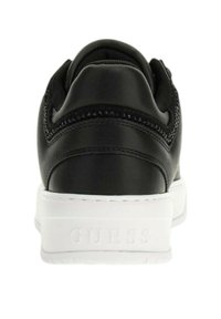 Sneaker in pelle nera con suola bianca, con il marchio "GUESS" visibile in rilievo sul tallone, vista dal retro.