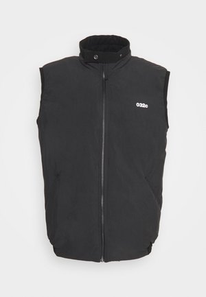 Black sleeveless vest with a high collar, front zipper, and side pockets. Features a white logo on the chest. Smooth fabric texture.