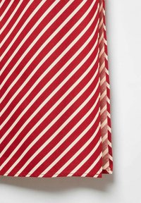 Tissu rayé diagonal rouge et blanc avec des bords d'ourlet propres, plié sur une surface blanche.