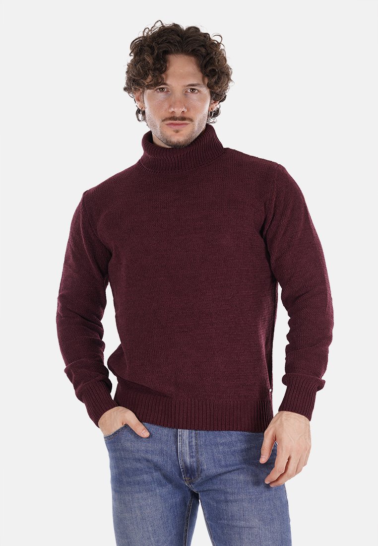 Maglione a collo alto borgogna in maglia testurizzata, con maniche lunghe e polsini e orlo a costine. Indossato con jeans blu.