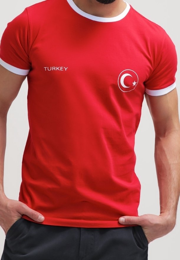 T-shirt en coton rouge avec des bords blancs, comportant le texte "TURQUIE" et un emblème circulaire du drapeau turc. Manches courtes, design ajusté.
