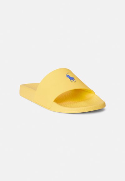 Κίτρινα σανδάλια με φαρδιά λουριά, κατασκευασμένα από καουτσούκ με υφασμένη σόλα, που διαθέτουν ένα ευρύ λουράκι και ένα μπλε λογότυπο με άλογο στο μπροστινό μέρος.