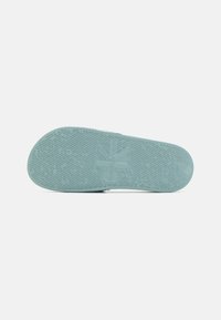Semelle de chaussure en caoutchouc vert présentant un motif texturé et un logo en relief. Forme arrondie avec une finition lisse et sans accents distincts.