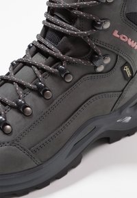 Grau Wanderschuh aus Nubukleder und Mesh, mit schwarzen Akzenten, rosa und grauen Schnürsenkeln sowie Metallhaken für einen sicheren Halt.