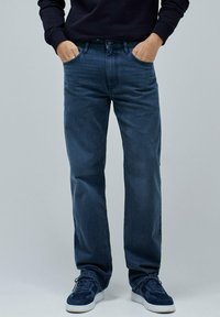 Temno modri jeans z ravnimi hlačnicami, petimi žepi, subtilno svetlečo teksturo in klasičnim zadrgo za zapiranje.