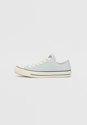 Light blue canvas sneaker with white rubber sole, black stripe detail, and six white eyelets for laces. Rounded toe cap and logo patch.
