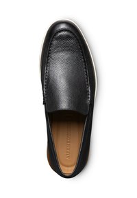 Scarpa slip-on nera in pelle con superficie testurizzata, punta tondeggiante e suola bianca a contrasto. L'interno è rifinito con una morbida fodera color cammello.