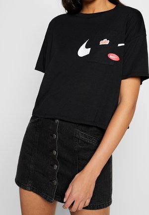 Black cropped t-shirt with white and red Nike logos, short sleeves, and a chest pocket. Paired with a black denim button-up skirt.