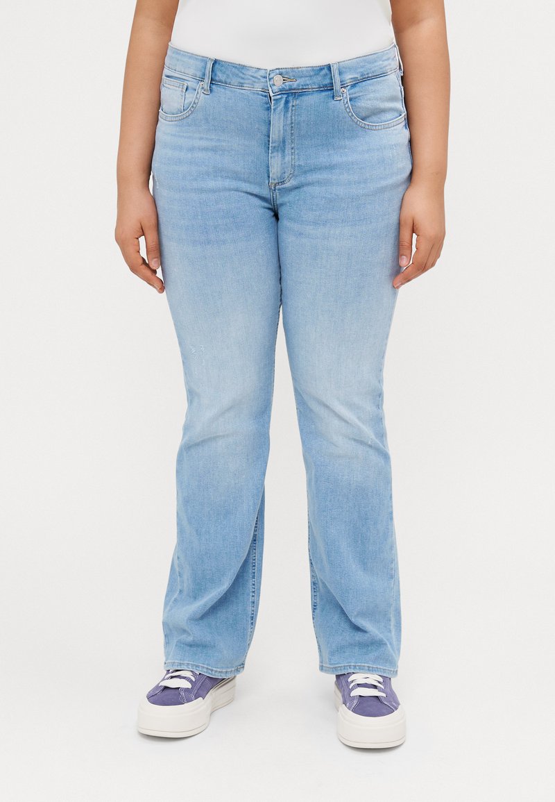 Light blue denim jeans with a straight-leg cut, five pockets, and stitching details, paired with white sneakers and a simple top.