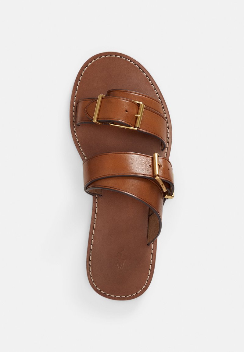 Brown leather sandal featuring two wide straps with a gold buckle, a smooth texture, and white stitching along the edges.