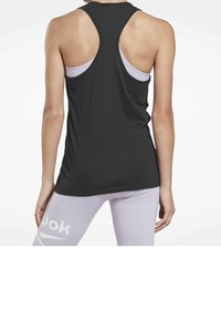 Černý tílko s racerback designem, vyrobené z lehkého materiálu. Má volný střih a mírně zakřivený lem. Kombinováno se světlými fialovými legínami.