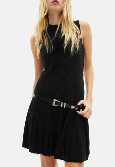 Vestito nero senza maniche con pieghe verticali, corpetto aderente e gonna svasata. Presenta una cintura nera con dettaglio fibbia in argento.