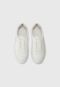 Vita lädersneakers med rund tå, platta snören, vadderad krage och minimalistisk design. Har diskret logotyp på innersulan.