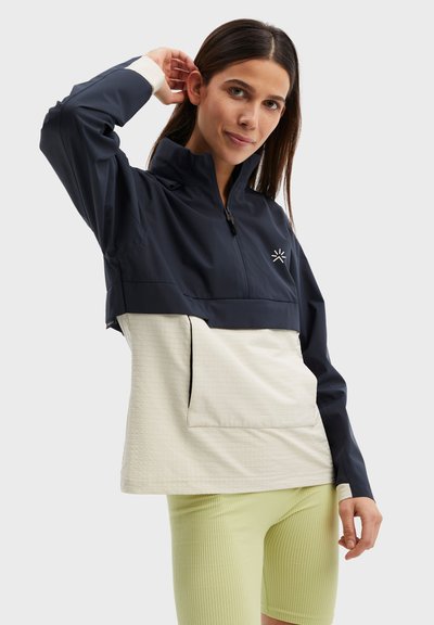 Marinblå och krämfärgad tvåtonspullover med ståkrage, halva dragkedjan och framficka. Strukturerad tyg med broderad logotyp på bröstet.