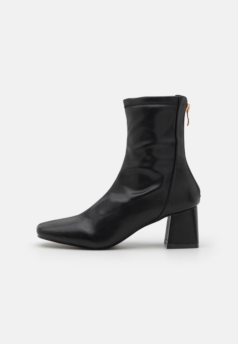 Botte en cuir noire mi-mollet avec bout carré, talon bloc et fermeture éclair arrière avec tirette dorée, vue de profil sur fond blanc.