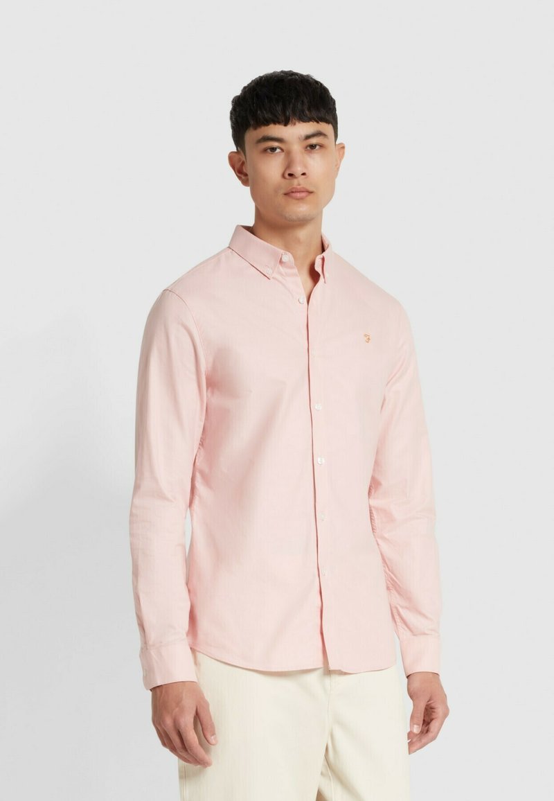 Camicia a maniche lunghe rosa chiaro con colletto alla francese e logo ricamato sul petto; il tessuto è liscio con una leggera lucentezza.