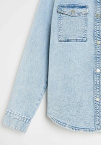Jasnoniebieska koszula z dżinsu z zapinaniem na guziki z przodu, jedną kieszenią na piersi oraz długimi rękawami z mankietami. Miękka tekstura, casualowy design.
