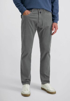 Pantaloni in corduroy grigi con design a gamba dritta, dotati di tasche frontali e chiusura a bottone. Abbinati a sneakers bianche.