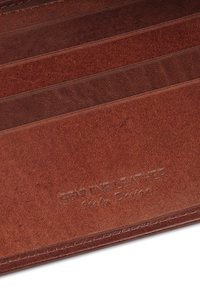 Wnętrze brązowego portfela skórzanego z wieloma przegródkami na karty; cechuje się gładką teksturą i wytłoczonym napisem "Genuine Leather" z jednej strony.