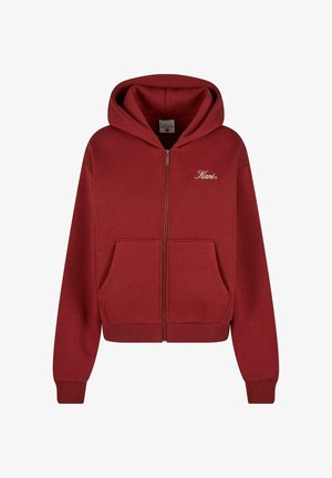 Sarkans kapucis džemperis ar rāvējslēdzēju, izgatavots no mīksta auduma, ar priekšējo kabatu, ribotiem piedurkņu galiem un izšūtu logo uz krūšu.