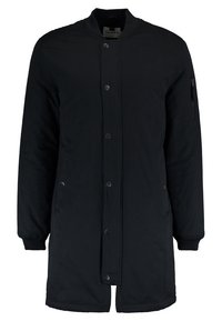 Zwarte bomberjack met een geribde kraag, een ritszak op de mouw, drukknoopsluiting en een licht gewatteerde structuur.