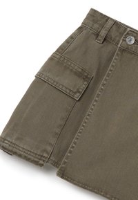 Falda cargo verde oliva, hecha de tela duradera con rayas verticales, presenta un bolsillo lateral y dobladillos cosidos.