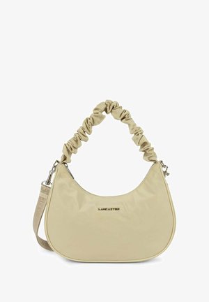 Sac à main en nylon beige avec une forme incurvée, une anse froncée et des accessoires en argent. Il présente un logo à l'avant et une sangle ajustable.
