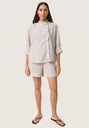 Stribet top og shorts sæt i blødt stof, med en flæseknapstolpe og trekvartærmer. Farverne er beige og grå striber.