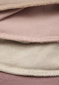 Miękkie warstwy dzianiny w jasnoróżowym, beżowym i blado kremowym kolorze; charakteryzują się widocznymi szwami i delikatną teksturą.