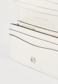 Hvid læderpung med flere kortlommer og en sølvfarvet tryklås. Har prægede mærker og fine sømdetaljer.