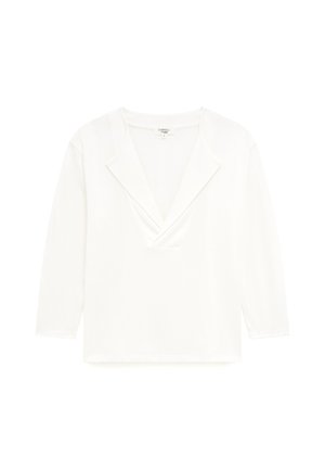 Top blanc léger à manches longues avec un décolleté en V profond et un design de col croisé. Texture lisse, ourlet droit.