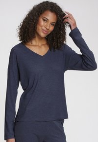 Navy blue long-sleeve top with a V-neck, made of ribbed fabric. Features a relaxed fit and subtle texture.