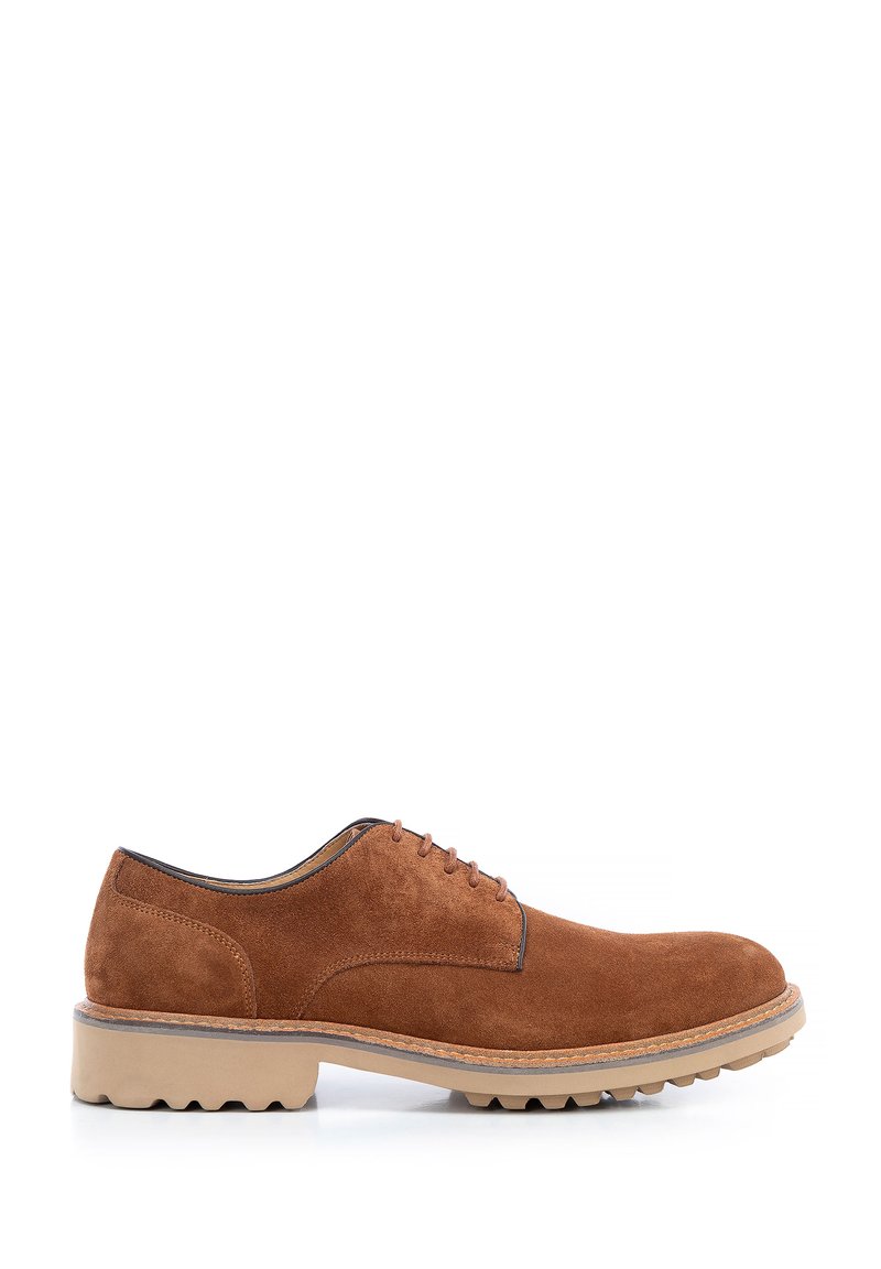 Scarpa in suede marrone con lacci e punta arrotondata, suola in gomma beige spessa e dettagli di cucitura discreti lungo i bordi.
