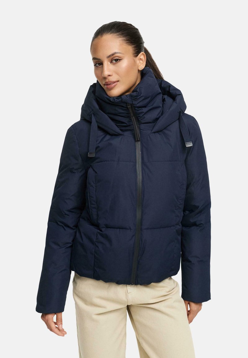 Navy puffer jacket with a high collar, front zipper, and large hood; features a quilted design and elastic drawstrings for adjustment.