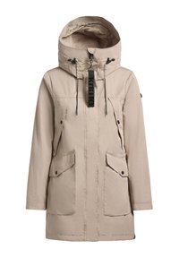 Parka impermeabile beige con cappuccio alto a colletto, due tasche anteriori e lacci neri. Presenta un'etichetta nera con logo sulla zip.
