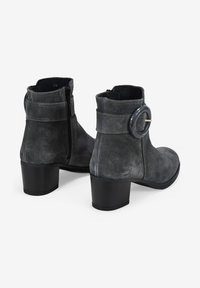 Botines de ante gris con un acento circular en el tobillo, tacón apilado y cremallera lateral para un fácil calzado.