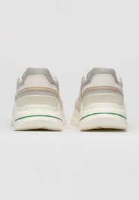 Sneaker in suede e rete beige con suola bianca, accenti grigi e una striscia verde sulla suola intermedia. Collare imbottito per il comfort.