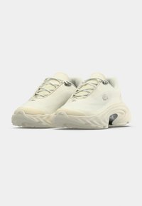 Ζευγάρι αθλητικών παπουτσιών μπεζ χρώματος με υφασμένους πάτους, σχέδιο με κορδόνια και διακριτικό κέντημα λογότυπου στα πλαϊνά.