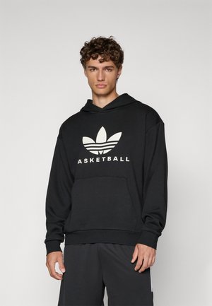 Svart hoodie i mjukt tyg med en stor vit Adidas-logotyp och texten "BASKETBALL". Med huva och framficka, avslappnad passform.