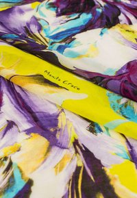 Écharpe jaune avec un motif floral dans des nuances de violet, bleu et blanc. Signature "Manila Grace" imprimée sur le tissu. Texture douce.