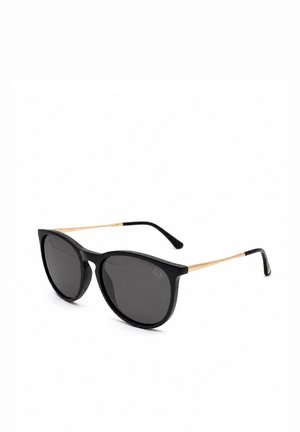 Schwarze Cat-Eye-Sonnenbrille mit dunklen Gläsern und dünnen goldenen Bügeln, die in schwarzen Enden auslaufen, vor einem weißen Hintergrund dargestellt.
