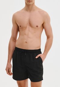 Czarne szorty kąpielowe wykonane z lekkiego materiału, z elastycznym paskiem w talii i przednimi kieszeniami, charakteryzujące się luźnym krojem i gładką teksturą.