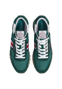 Baskets vertes avec des lacets blancs, rayures rouges, blanches et bleues sur les côtés, et étiquettes de marque sur les languettes et les côtés, montrées de dessus.