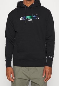 Sudadera negra con capucha y bolsillo canguro, con un diseño de texto multicolor. Fabricada con un tejido suave y texturizado; puños y dobladillo acanalados.