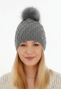 Grijze gebreide muts met een kabelpatroon en een grote grijze bont pompon bovenop. Voorzien van een klein metalen accent.