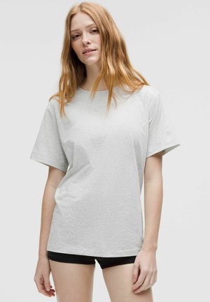 Tricou din bumbac gri deschis, cu mâneci scurte, decolteu rotund și croială lejeră, având o textură netedă și un design minimalist.