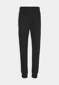 Schwarze Jogginghosen aus weichem Stoff mit einem komfortablen elastischen Bund, zulaufenden Beinen und einer einzelnen Gesäßtasche.